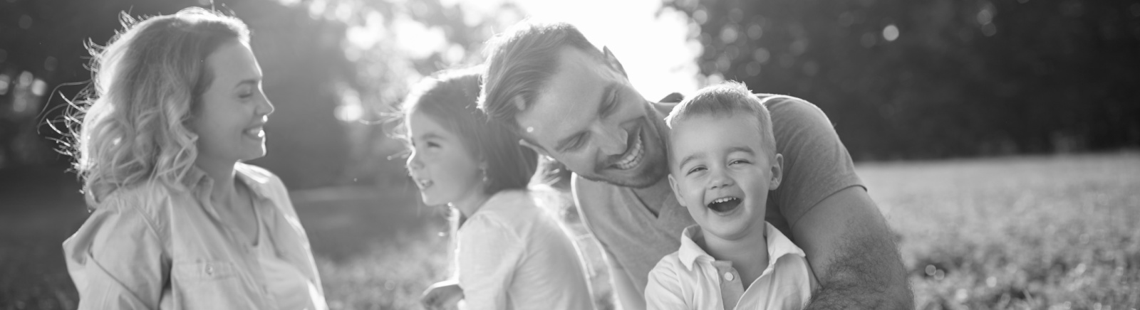 family sitting in a field, smiling